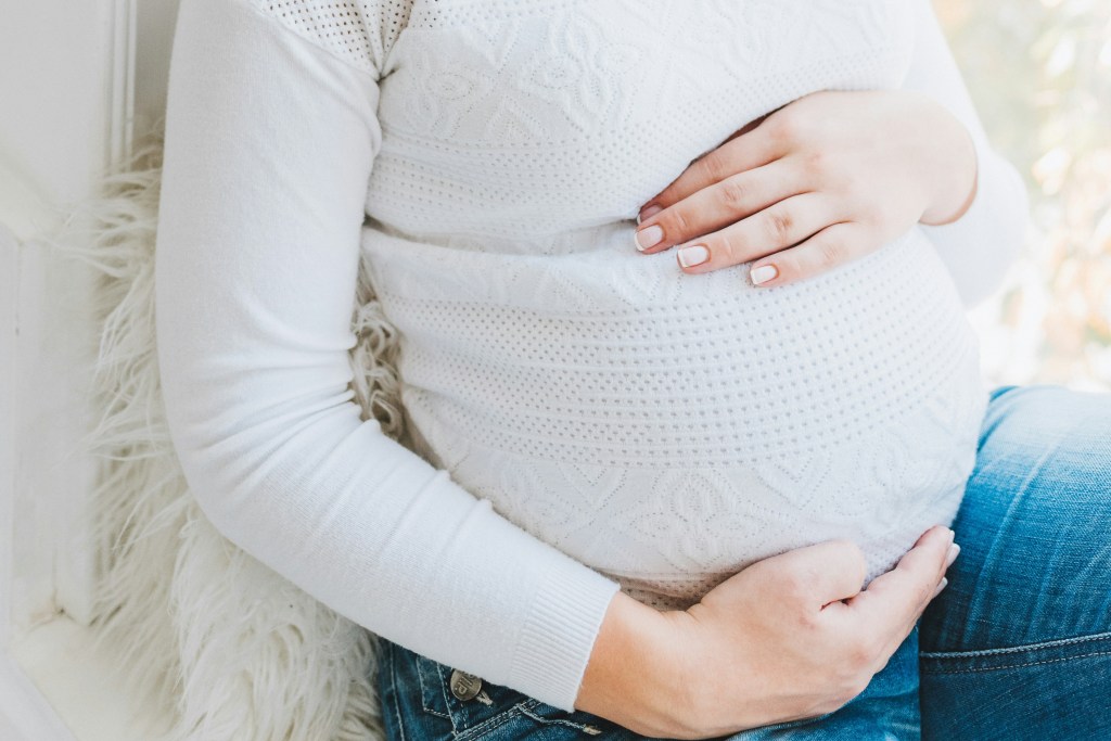 Close up photo of pregnant woman placing hands around her belly
