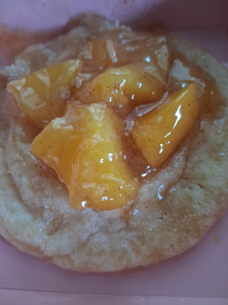 the peach cobbler cookie features a sugar cookie  topped with peach cobbler filling.