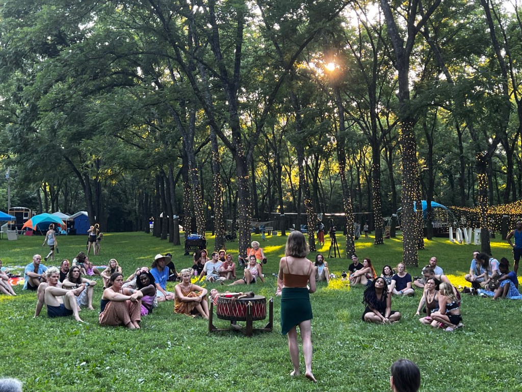 New Earth attendees sitting in the grass attending an outdoor workshop.